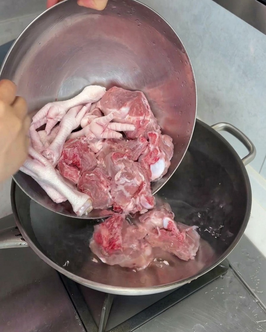 생 돼지 사골과 닭발을 물이 담긴 냄비에 넣어 데치는 모습.