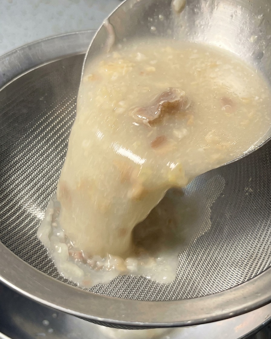 진하고 불투명한 뽀얀 육수를 고운 체에 걸러 볼에 부으며 고형물을 걸러내는 모습