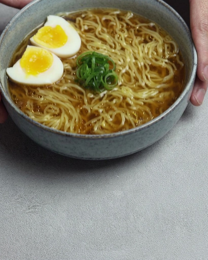 치킨 스톡이 담긴 냄비에 유리 계량컵으로 물을 붓는 모습.