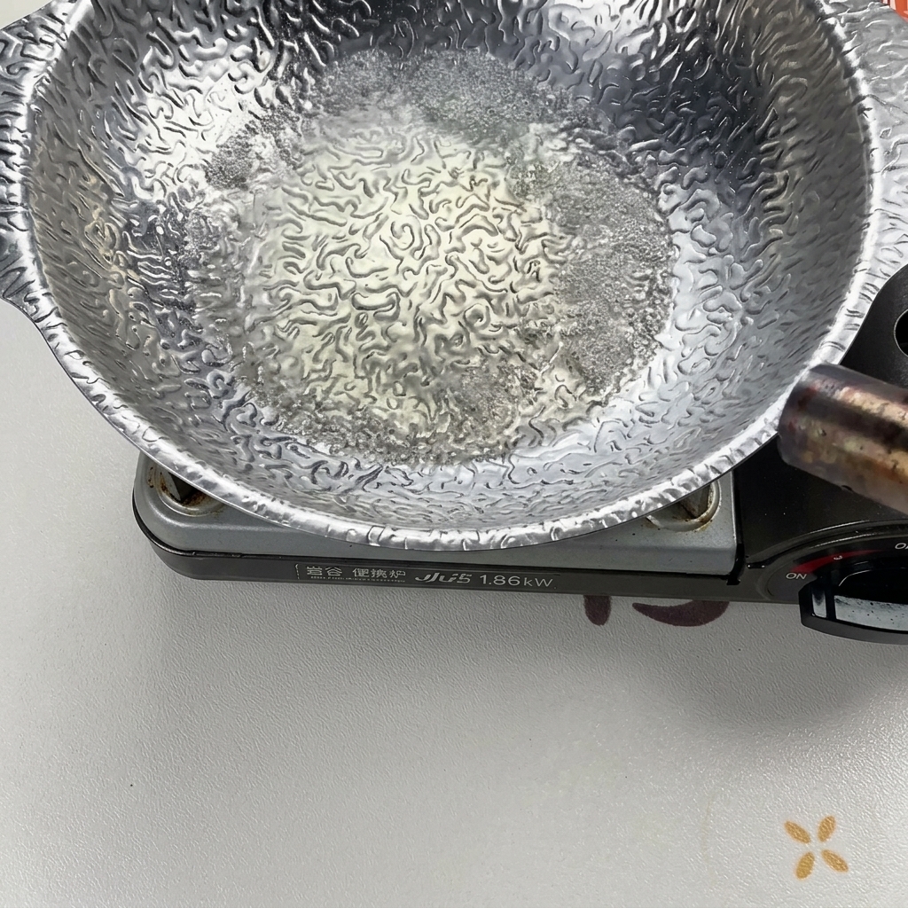 은색 냄비에서 끓고 있는 액체에 토치로 불을 붙여 알코올을 날리는 모습.