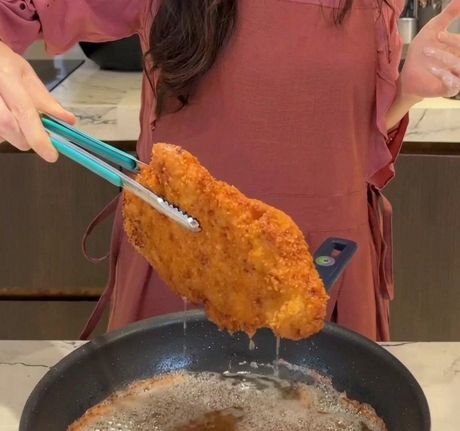 파란 집게를 이용해 팬에서 노릇하고 바삭한 돈까스를 건져 올리자 기름이 아래로 뚝뚝 떨어지는 모습