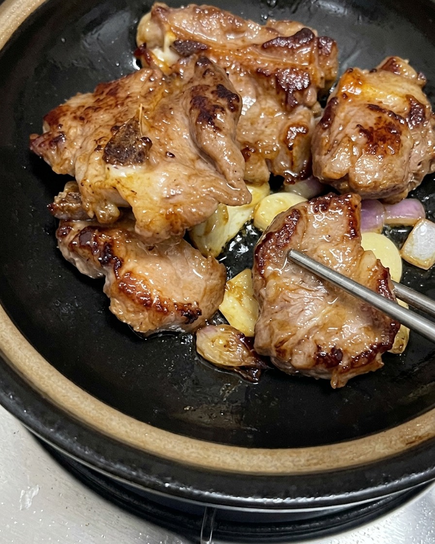 검은색 뚝배기 안에서 잘 볶아진 마늘과 샬롯 위에 차곡차곡 올려진 노릇한 돼지갈비.