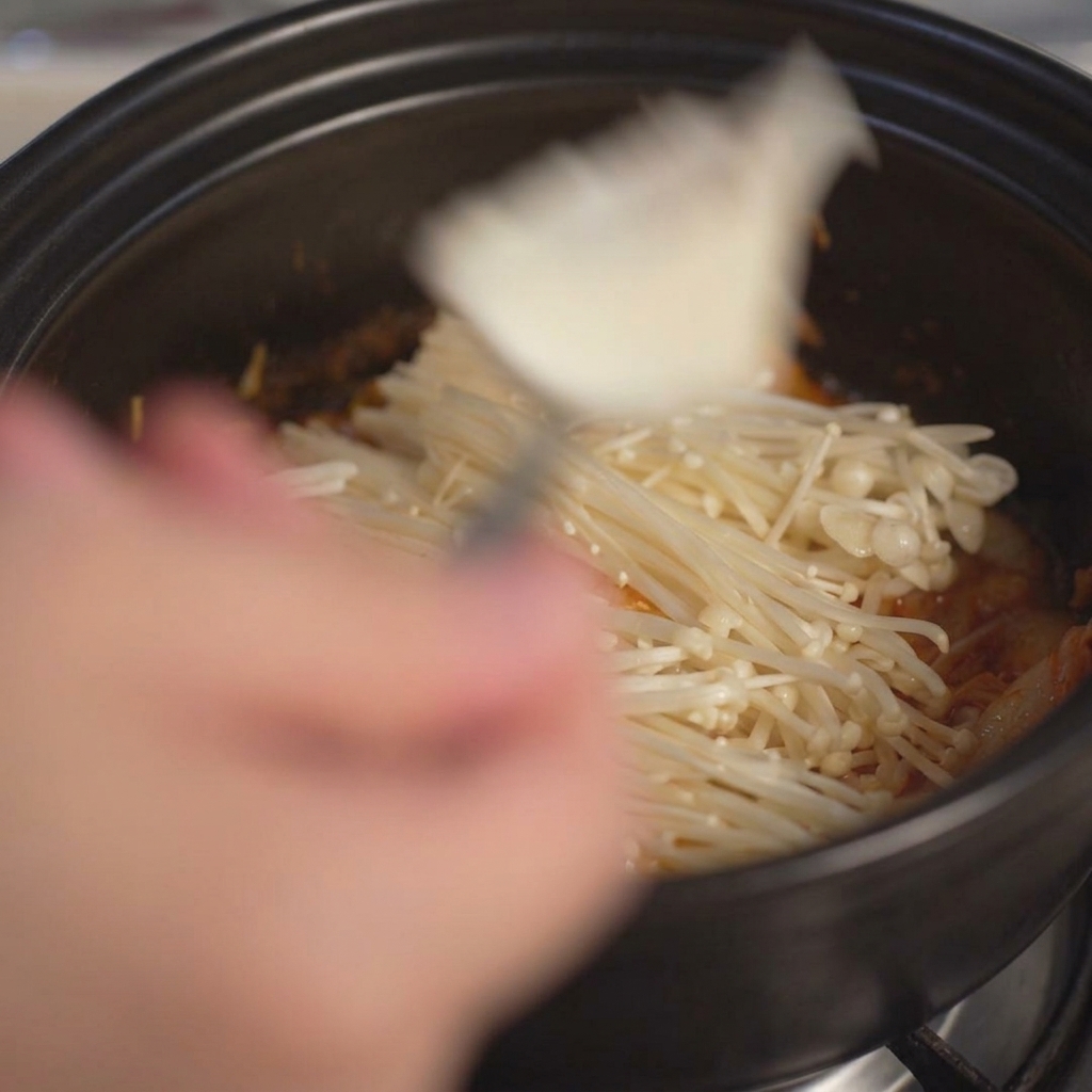 숟가락을 이용해 큼직하게 뜬 하얀 순두부를 뚝배기 안에 넣는 모습