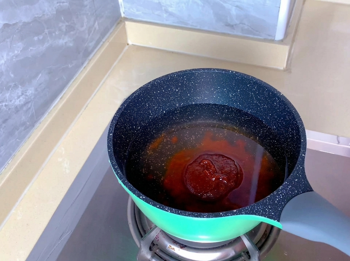 초록색 냄비 속 맑은 물에 붉은색 김치찌개 양념이 풀어지고 있는 모습