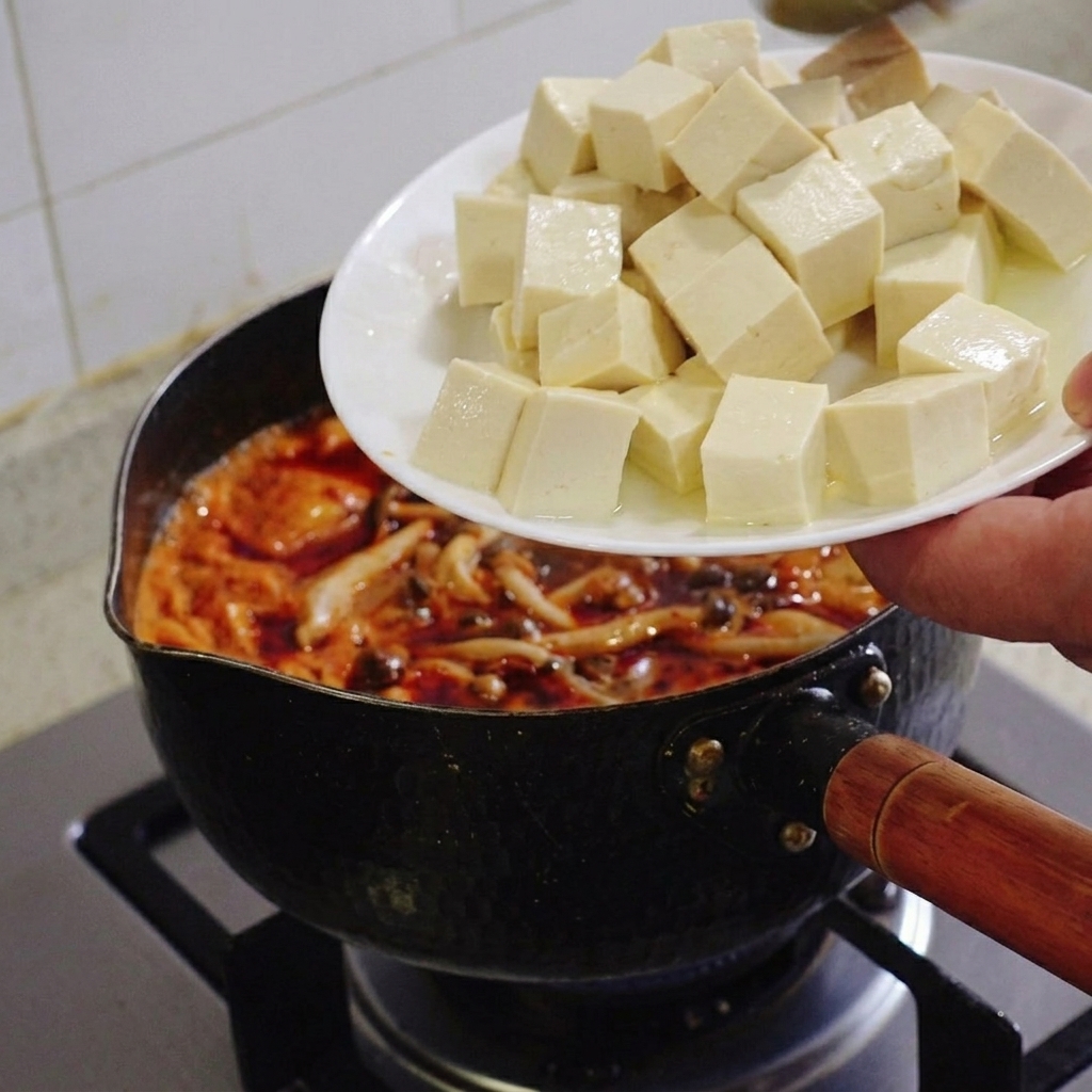 김치찌개 국물에 도톰하게 썬 하얀 순두부를 조심조심 넣는 모습