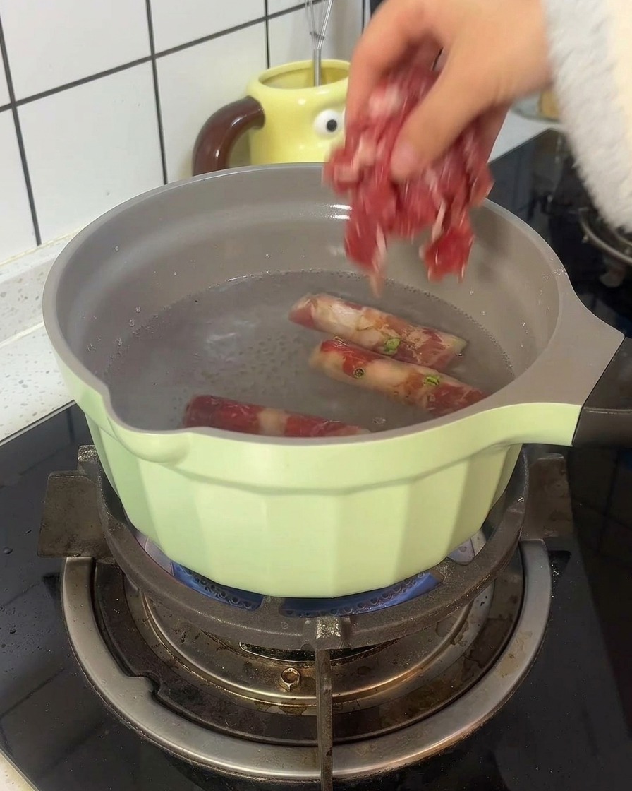 끓는 물이 담긴 냄비에 얇은 소고기를 데치는 모습.