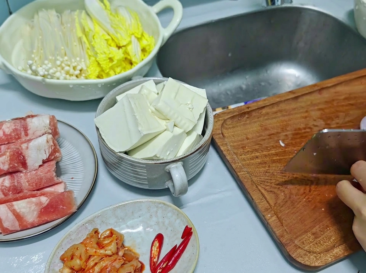 나무 도마 위에서 주방 칼로 적양파와 홍고추를 다지듯 썰고 있는 모습