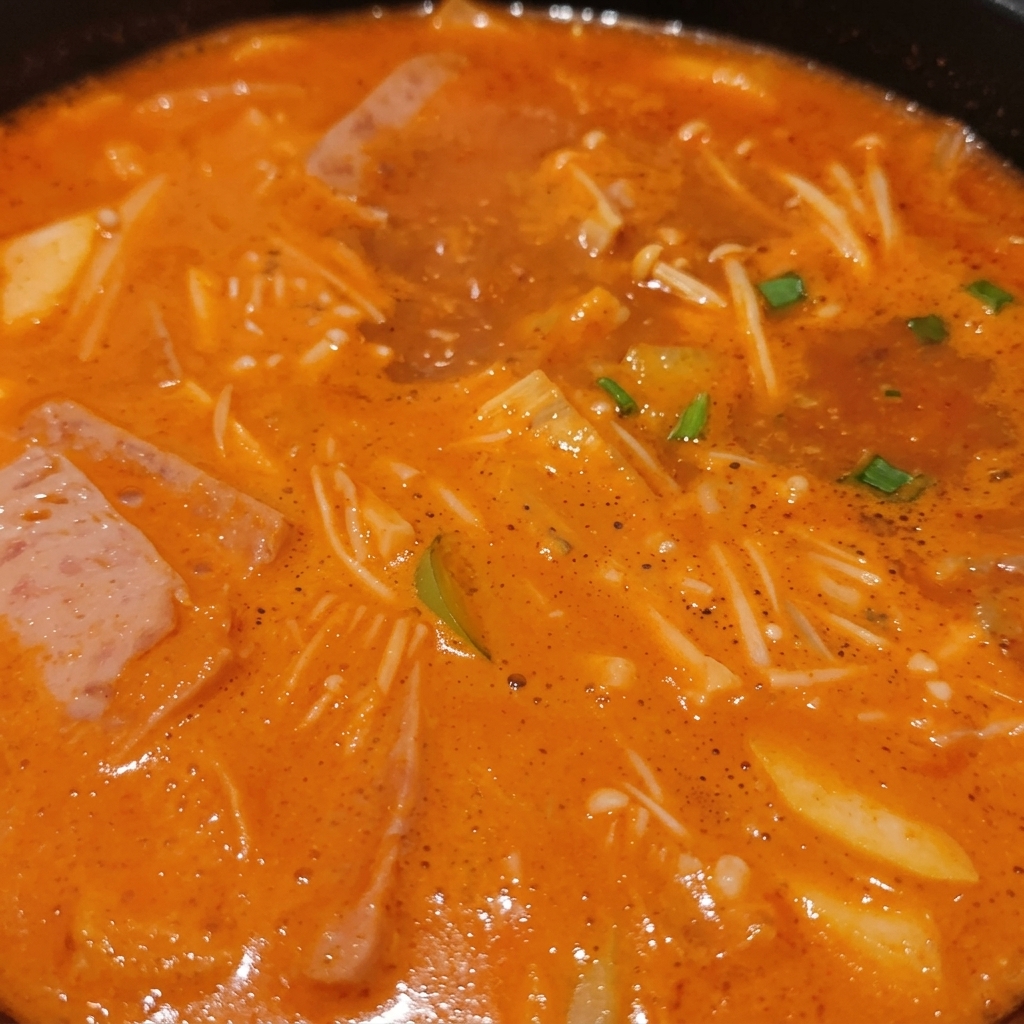 팽이버섯, 두부, 고기, 송송 썬 파가 진한 국물과 함께 보글보글 끓고 있는 뚝배기 속 모습
