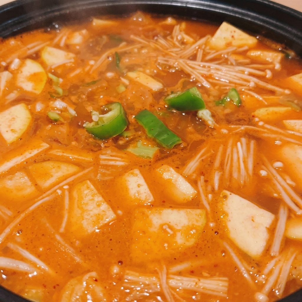 완성된 검은색 뚝배기 된장찌개 위에 초록색 청양고추 송송 썬 고명이 올라간 모습