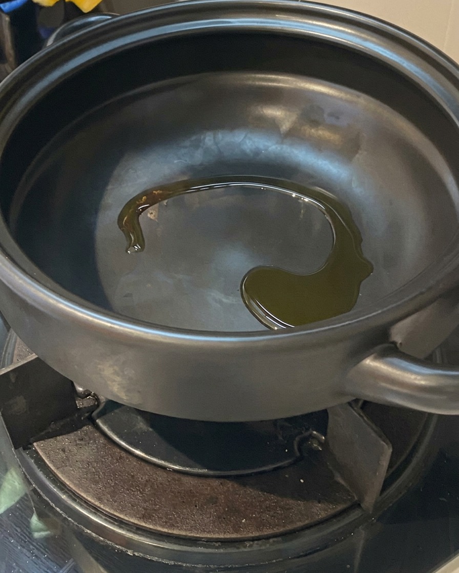 가스레인지 위에서 달구어진 검은색 뚝배기 바닥에 반짝이며 흐르는 식용유.