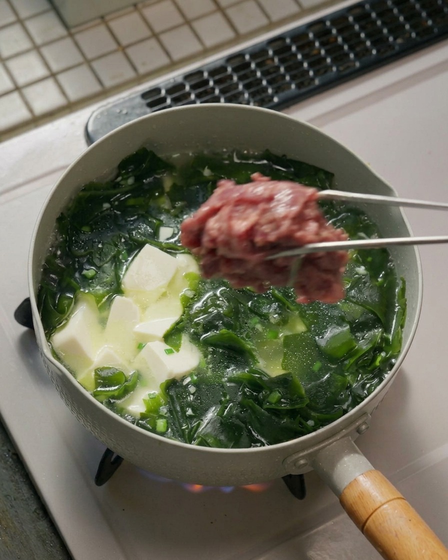 양념한 소고기를 끓는 국물에 넣는 모습.