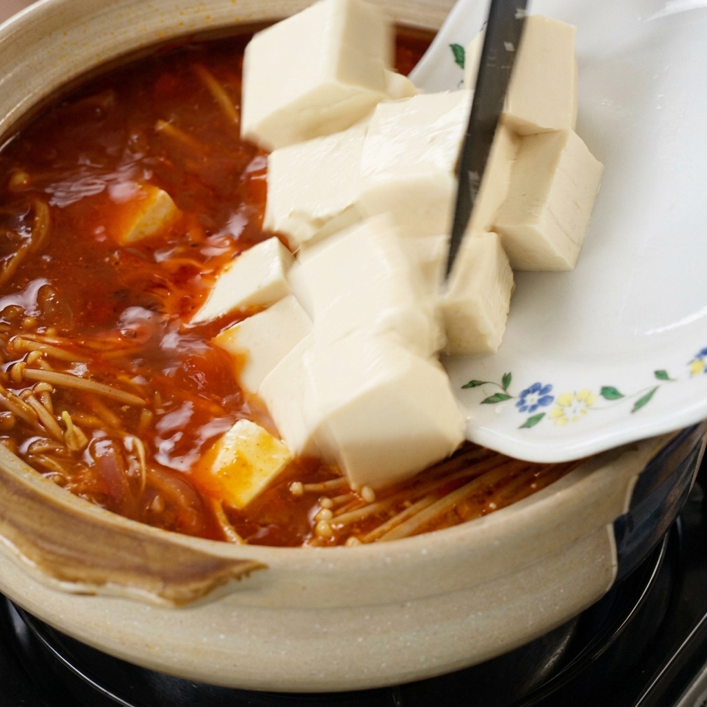 찌개에 두부와 팽이버섯을 넣는 모습