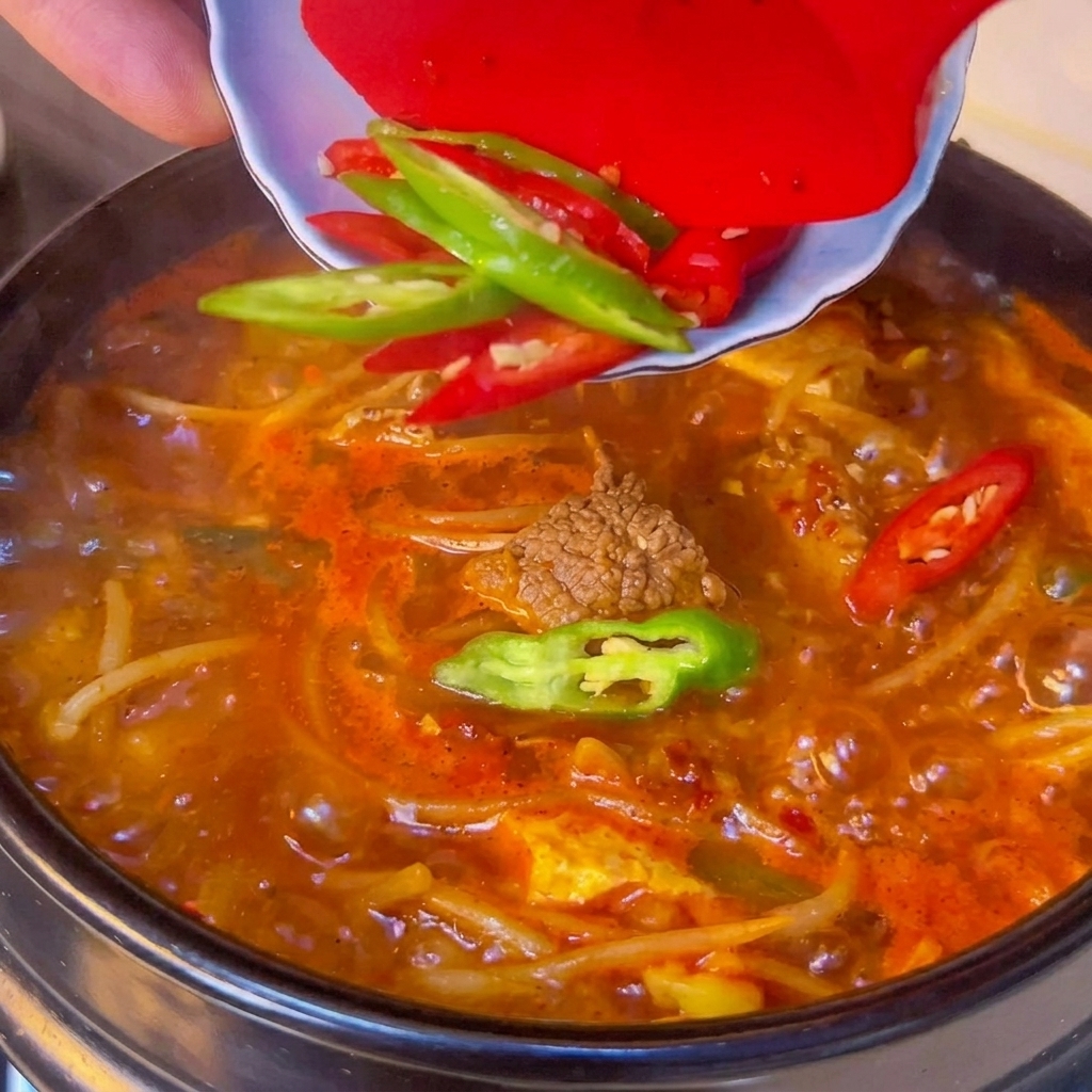 마지막에 청양고추와 홍고추 슬라이스를 찌개 위에 올리는 모습.