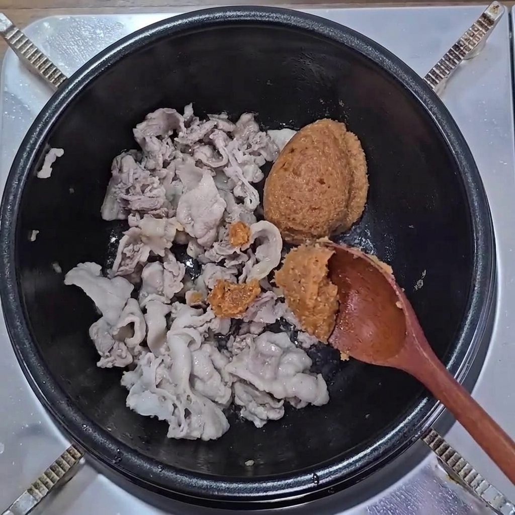 다 익은 삼겹살이 있는 냄비에 된장과 쌈장이 더해진 모습.
