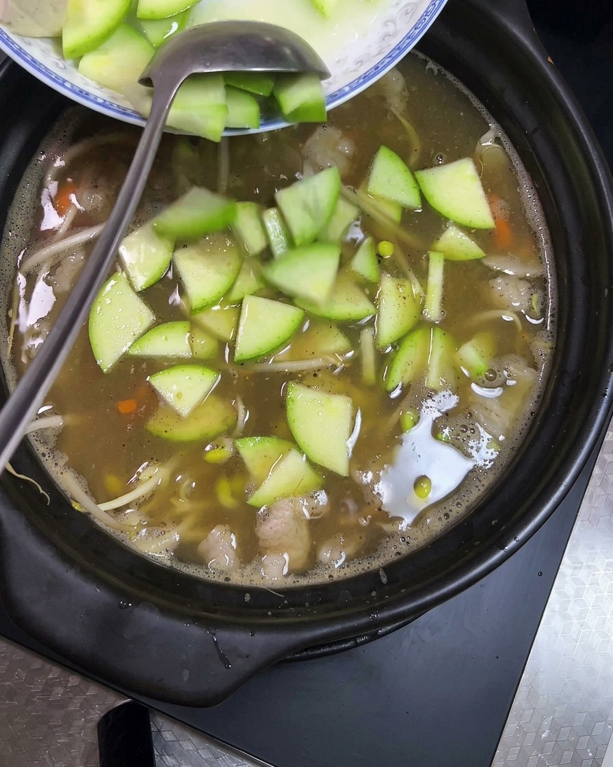 보글보글 끓는 뚝배기에 깍둑썰기한 두부와 슬라이스한 초록색 애호박을 넣는 모습.