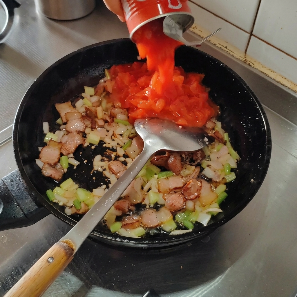 볶은 재료 위에 캔 토마토를 붓는 모습.