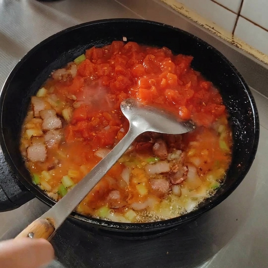 스패출러로 토마토를 으깨며 끓이는 모습.