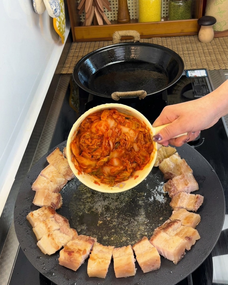 팬 가장자리에 고기를 배치하고 중앙에 김치를 놓아 볶는 모습.