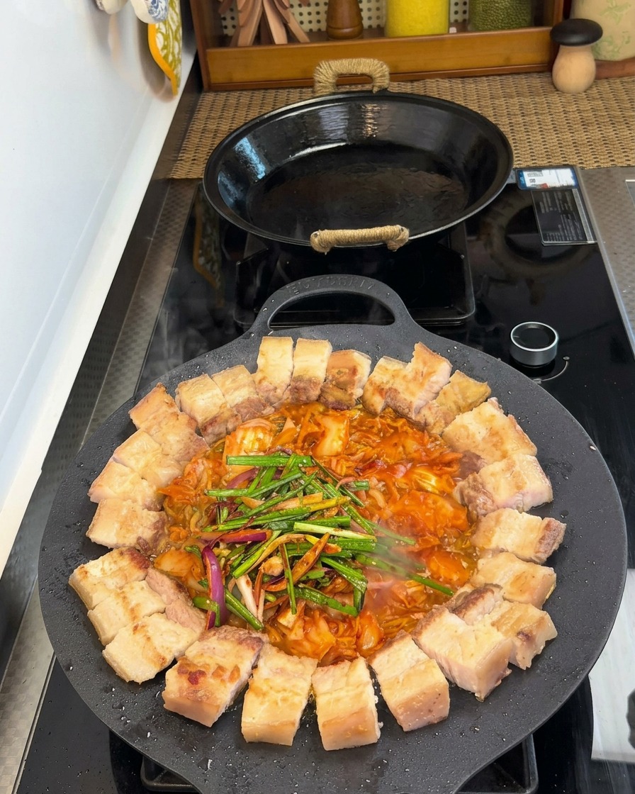 삼겹살과 김치 위로 대파, 양파, 양념 재료가 올라가 있는 모습.