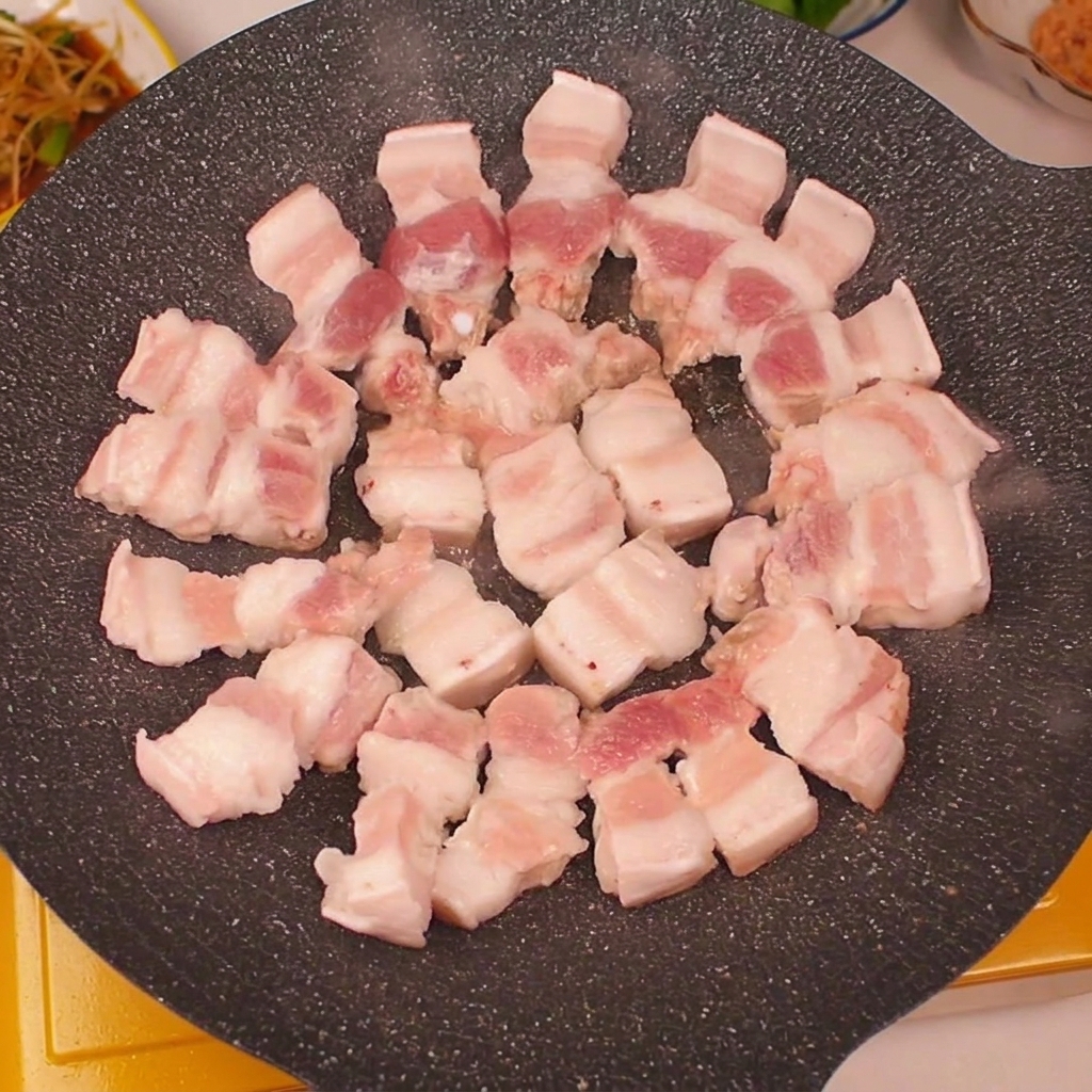 달궈진 팬 가장자리에 삼겹살을 가지런히 놓은 모습.