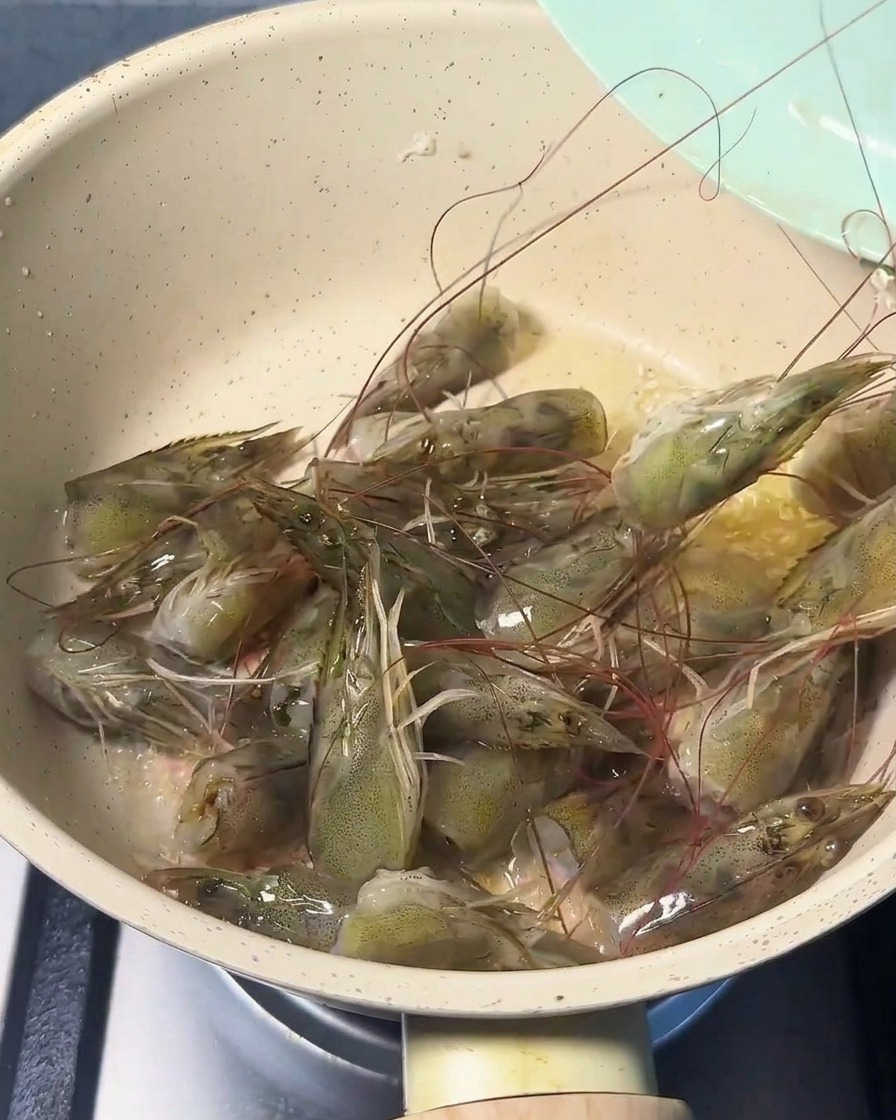 기름을 두른 팬에서 지글지글 익으며 붉게 변하는 신선한 새우 머리