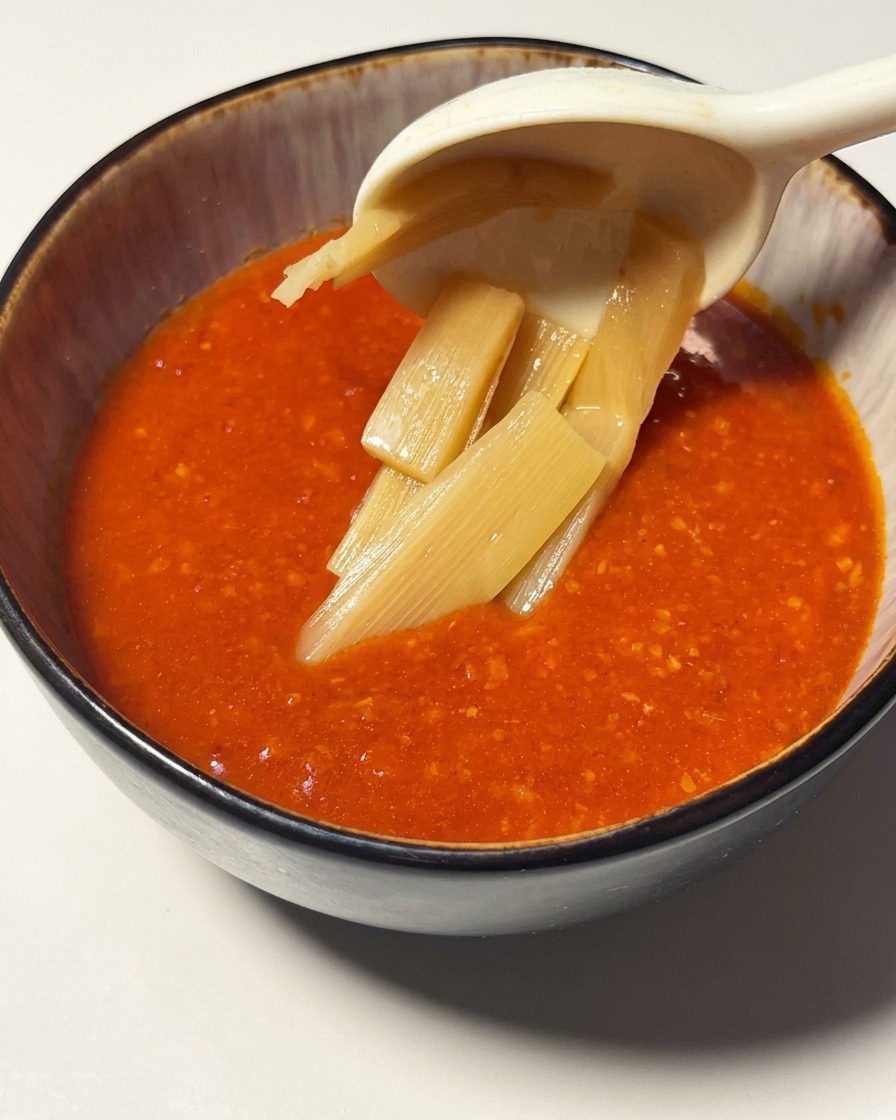 선명한 색감의 토마토 새우 소스가 담긴 그릇에 얇게 썬 죽순을 올리는 모습
