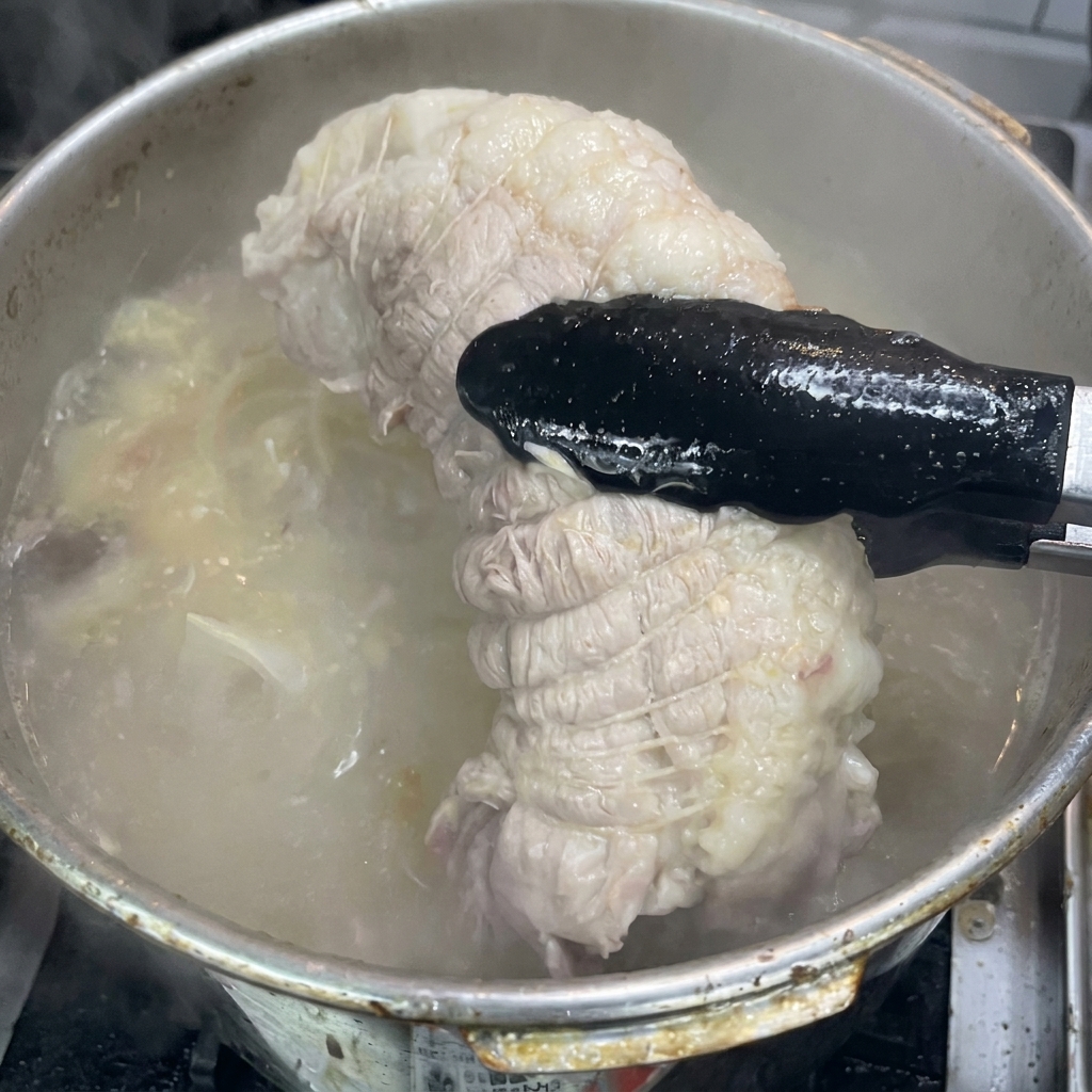 집게로 냄비에서 익은 고기를 꺼내는 모습.