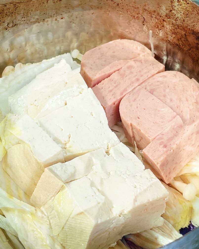 다른 재료가 담긴 냄비 중앙에 라면 사리를 올리는 모습.