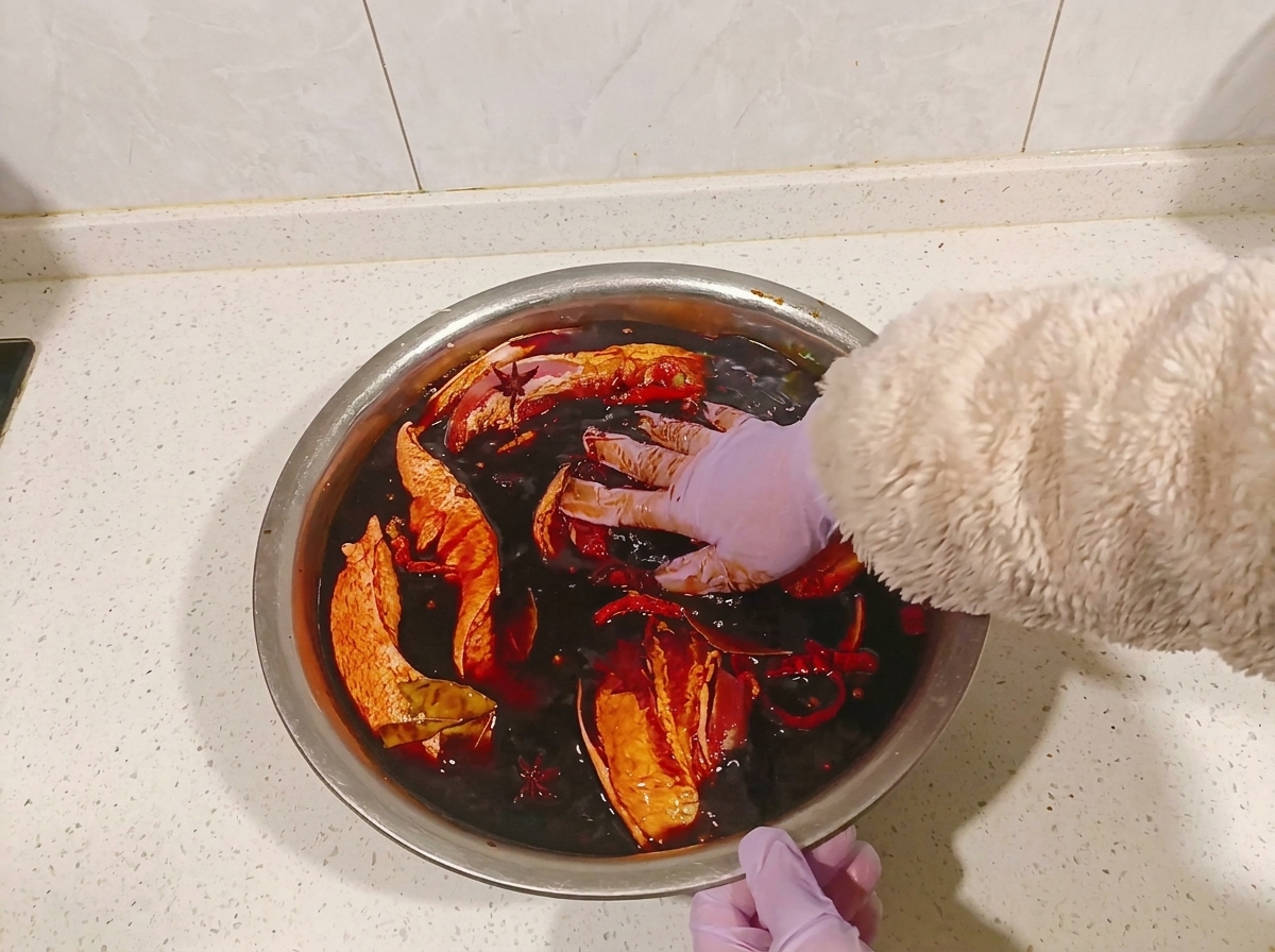 간장 양념에 담긴 삼겹살을 장갑 낀 손으로 뒤집는 모습.