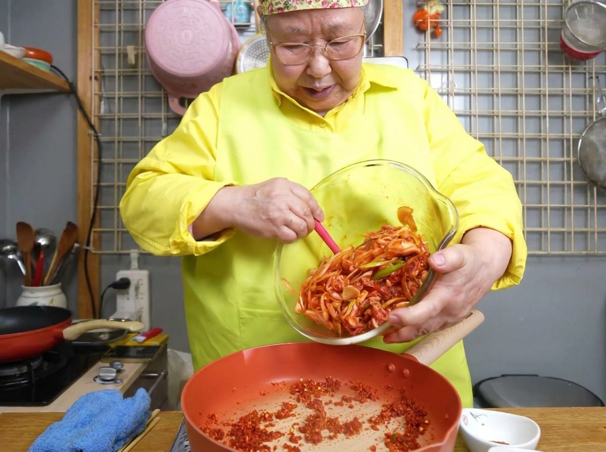 뜨거운 팬에서 얇게 썬 삼겹살과 다채로운 채소를 섞어가며 볶는 모습.