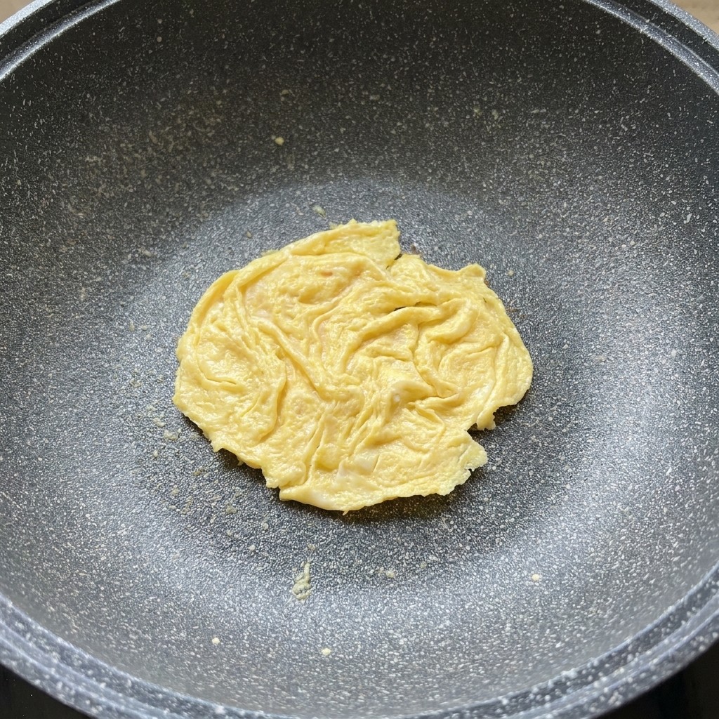 팬 속 달걀 패티 위에 치즈를 올리고 뚜껑을 덮어 녹이는 모습.