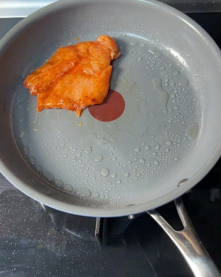 기름을 살짝 두른 뜨거운 팬에 생 치킨 패티를 올리는 모습.