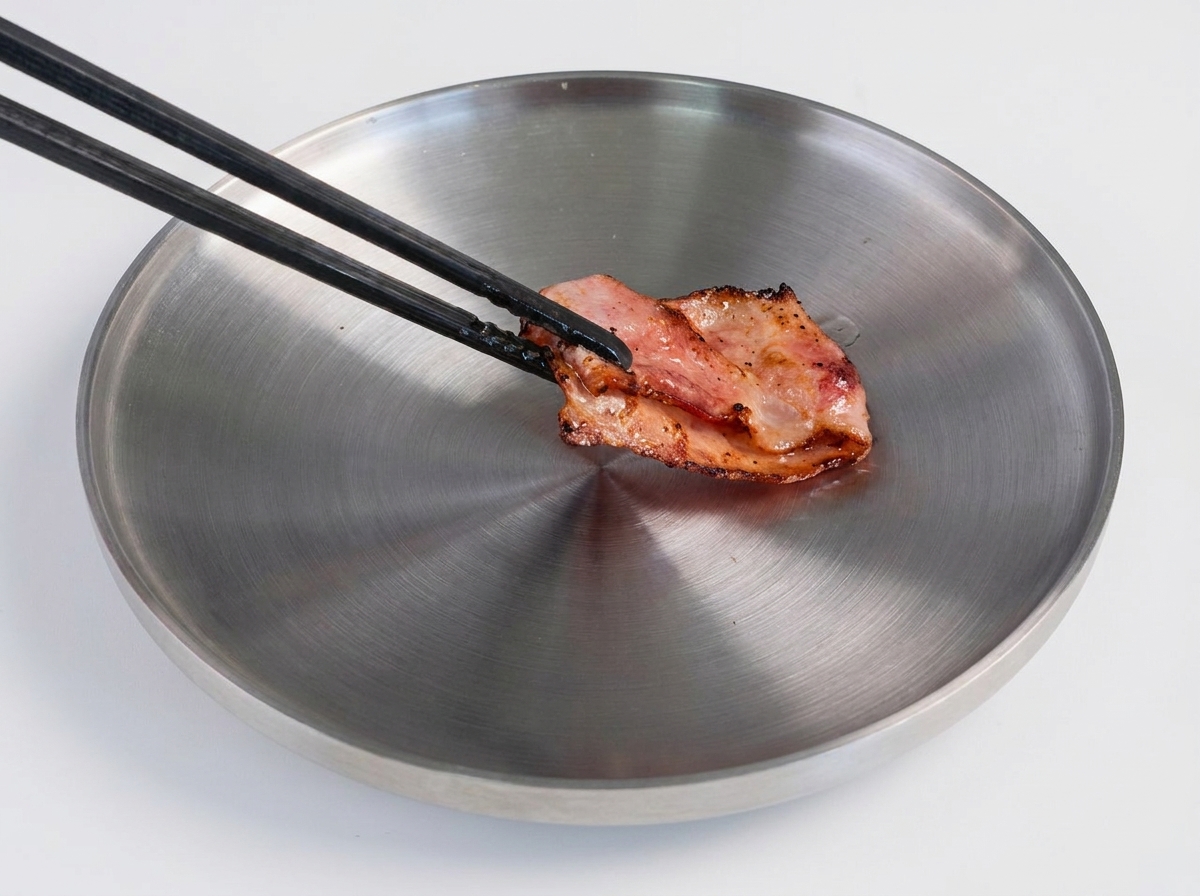 뜨거운 프라이팬에서 노릇하게 구워진 패티를 주걱으로 뒤집는 모습.