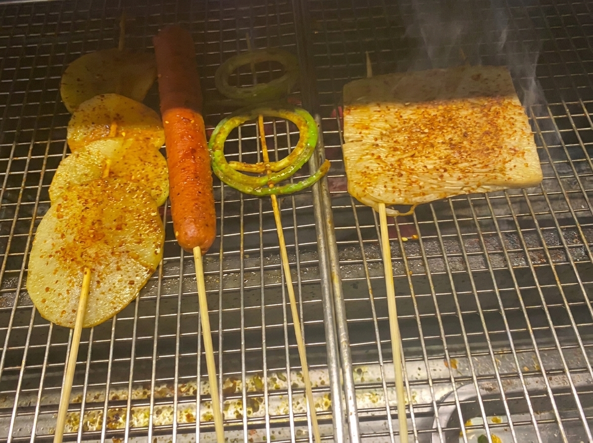 윤기 나는 바비큐 소스와 고춧가루가 뿌려진 구운 감자, 소시지, 채소들.