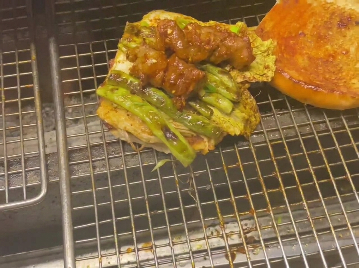 그릴 위에서 구운 채소와 글레이즈드 고기 꼬치가 올려진 버거 번 아래쪽.