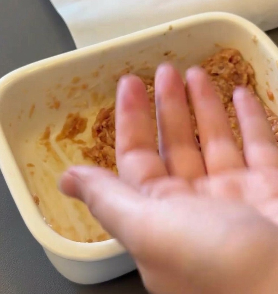 생고기 반죽을 둥근 패티 모양으로 빚고 있는 손.
