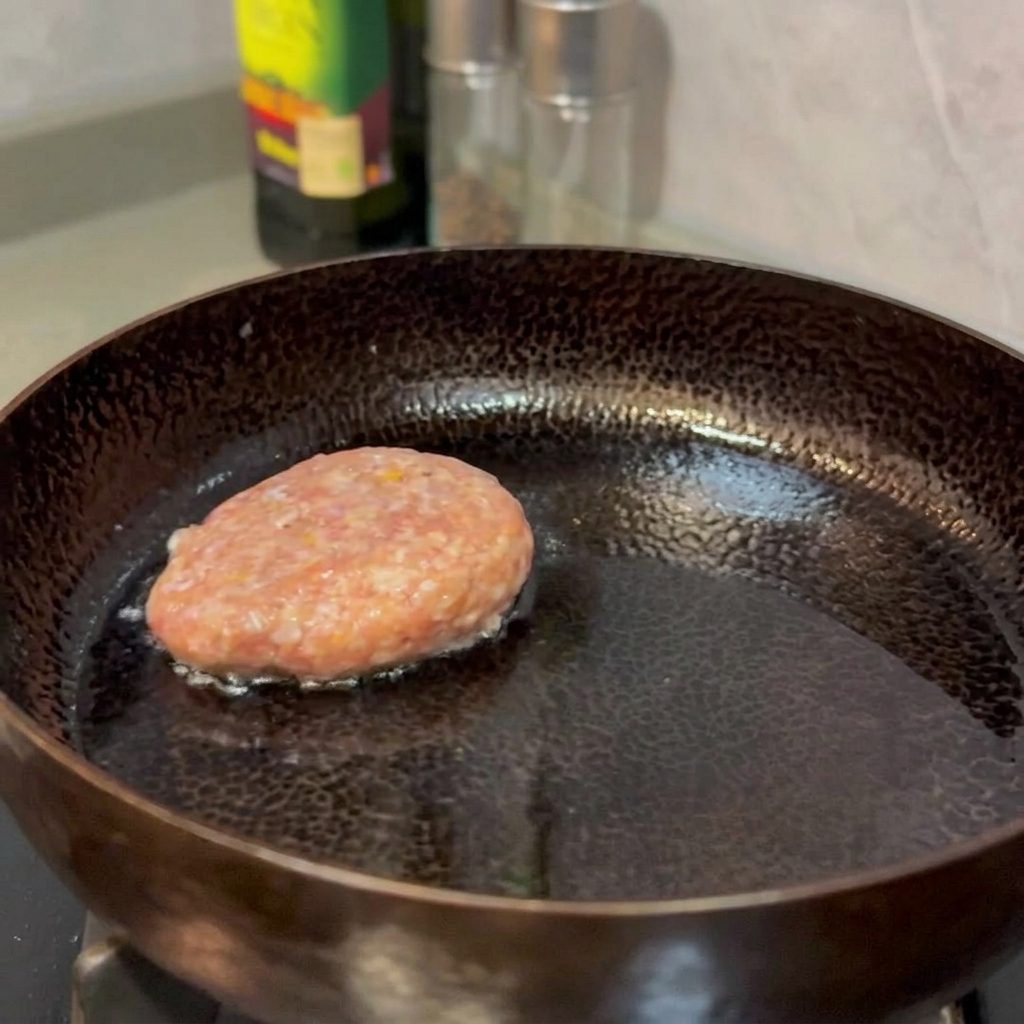 팬에서 노릇노릇해질 때까지 구워지고 있는 쇠고기 패티.