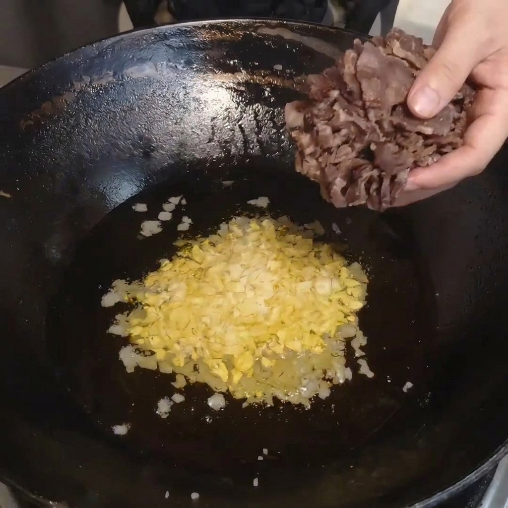 그릇에 담긴 찐 건조 소고기를 달궈진 웍으로 옮기는 모습.