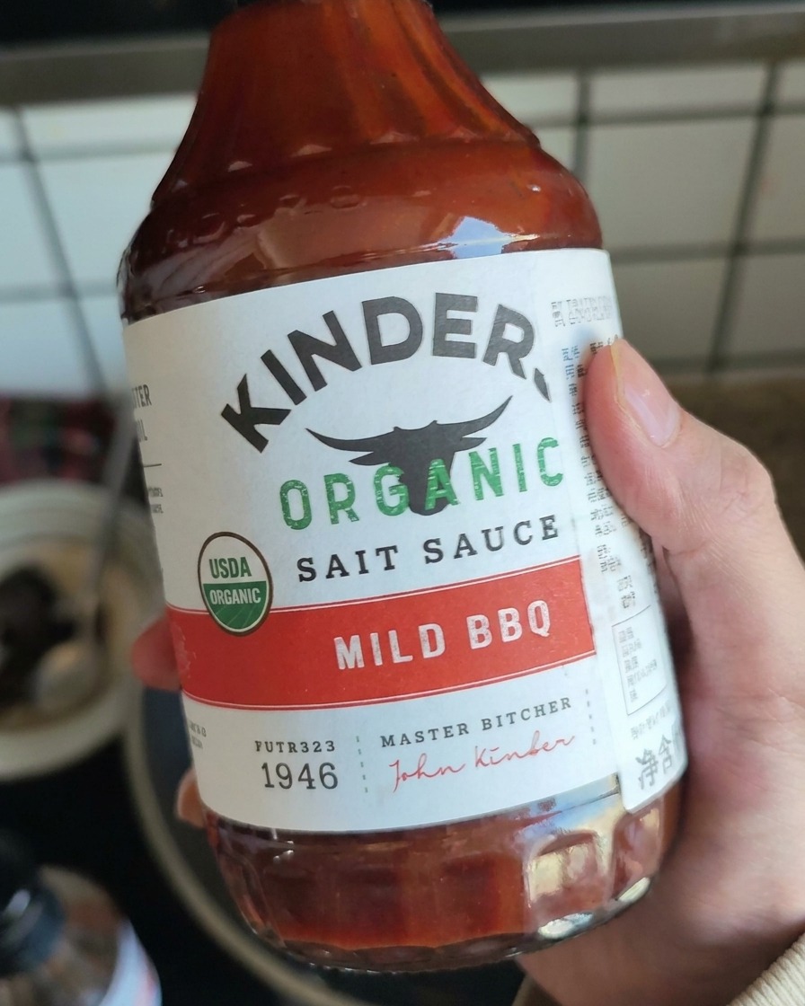찢어놓은 고기에 마일드 BBQ 소스를 넣으려는 손.