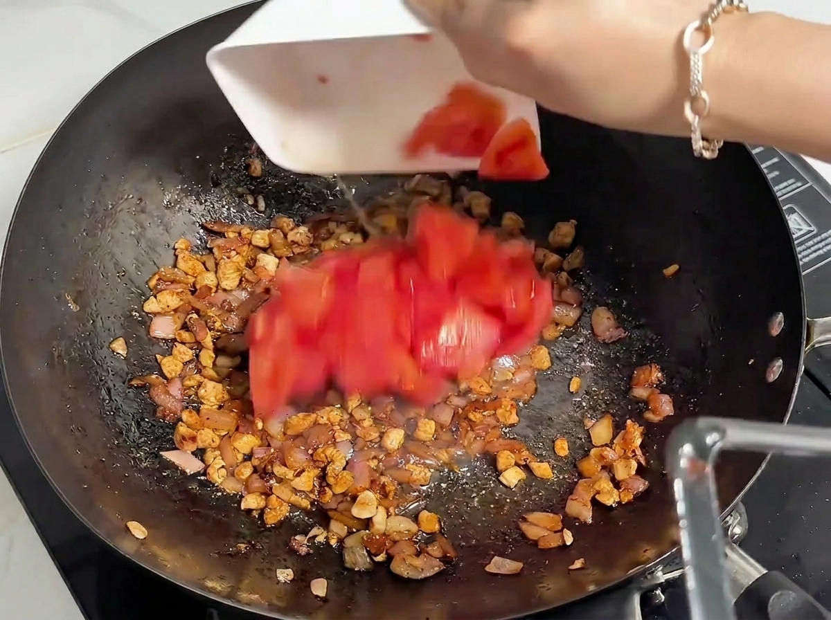 볶은 고기에 잘게 썬 토마토를 넣는 모습.