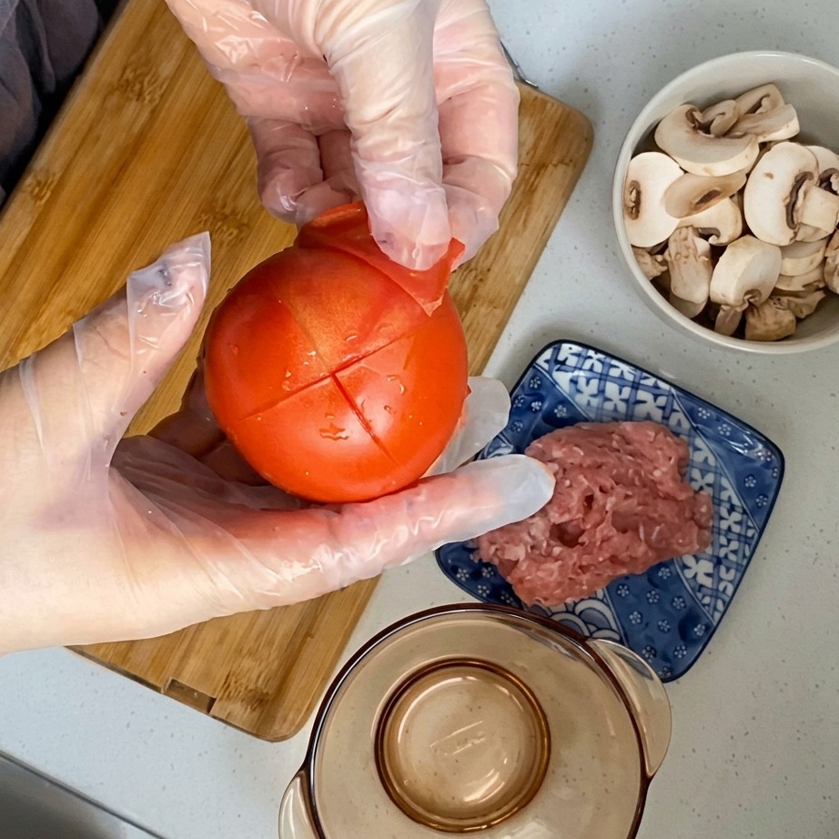 칼집을 내어 데친 토마토의 껍질을 벗기는 모습.