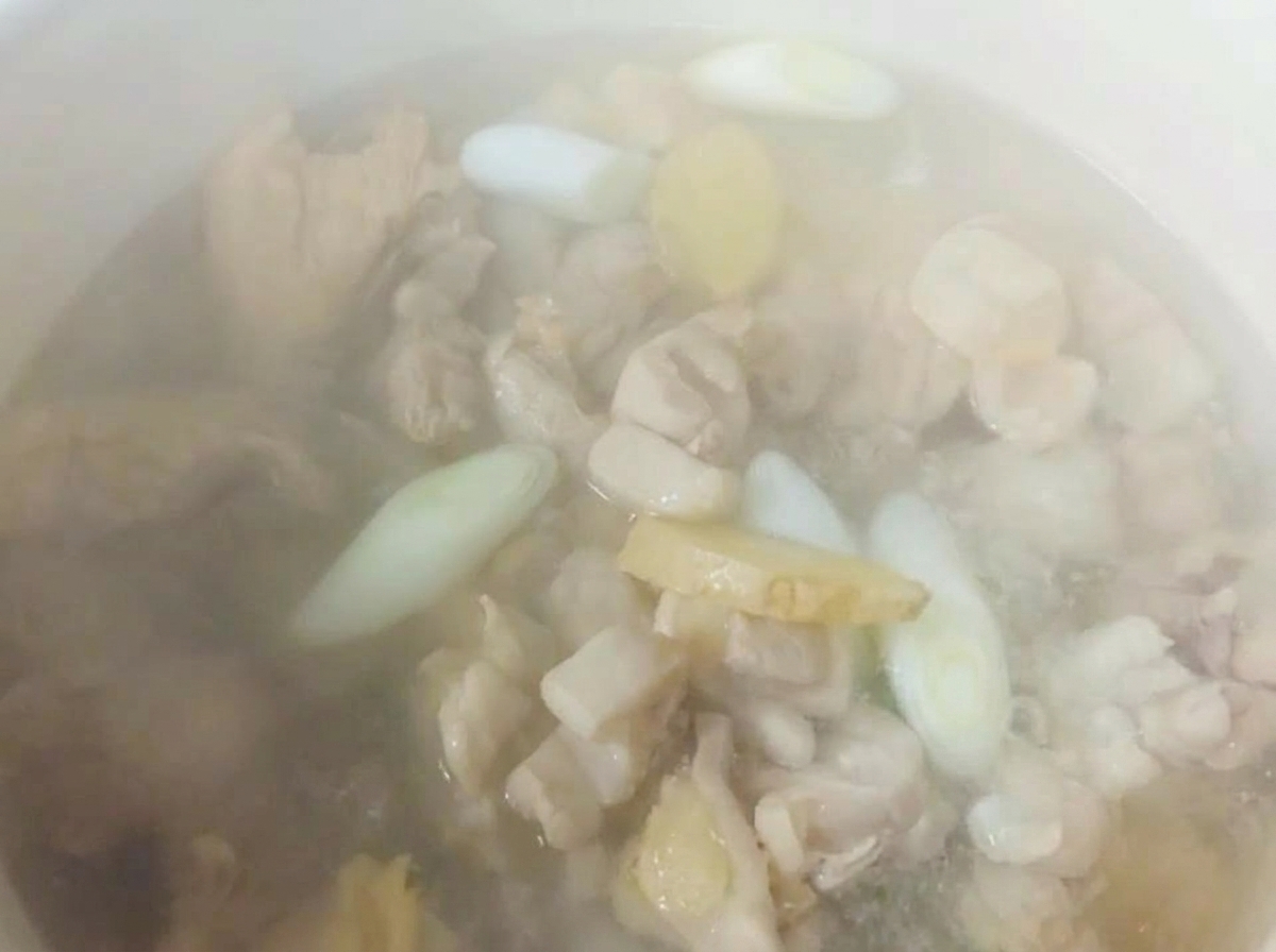 닭고기와 향신채 위에 뜨거운 물이 부어지며 김이 나는 모습.