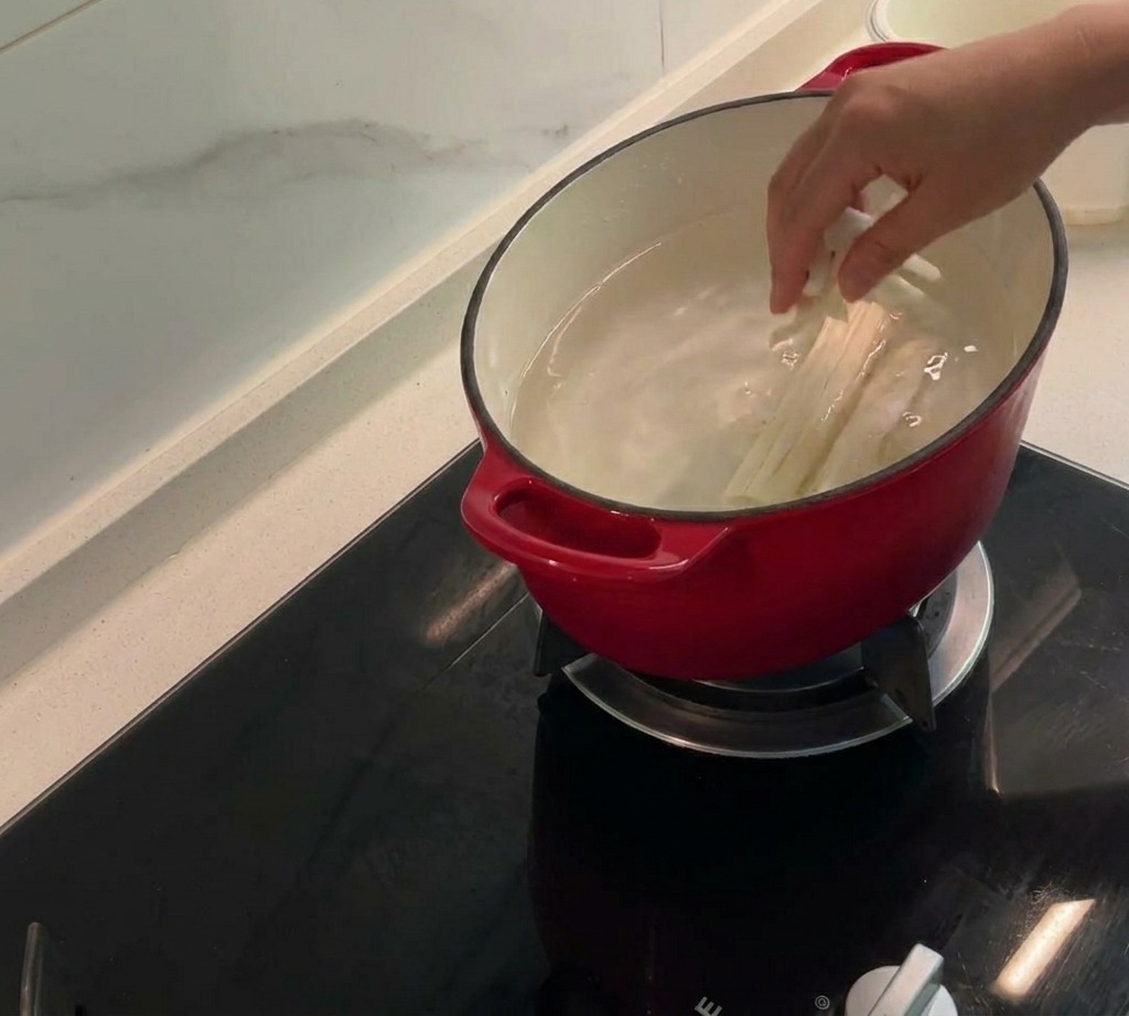냄비의 끓는 물에 옥수수 수염, 속대, 닭 껍질을 넣고 감칠맛 나는 육수를 우려내는 모습.