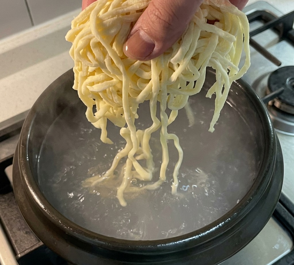 끓고 있는 닭고기 육수에 생면을 넣는 모습.