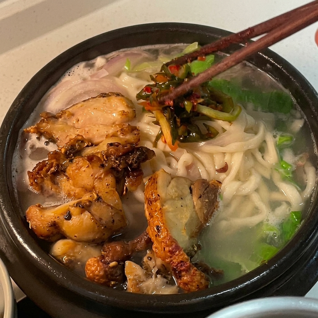 치킨 누들 수프 위에 선명한 붉은색 파김치를 고명으로 얹는 모습.