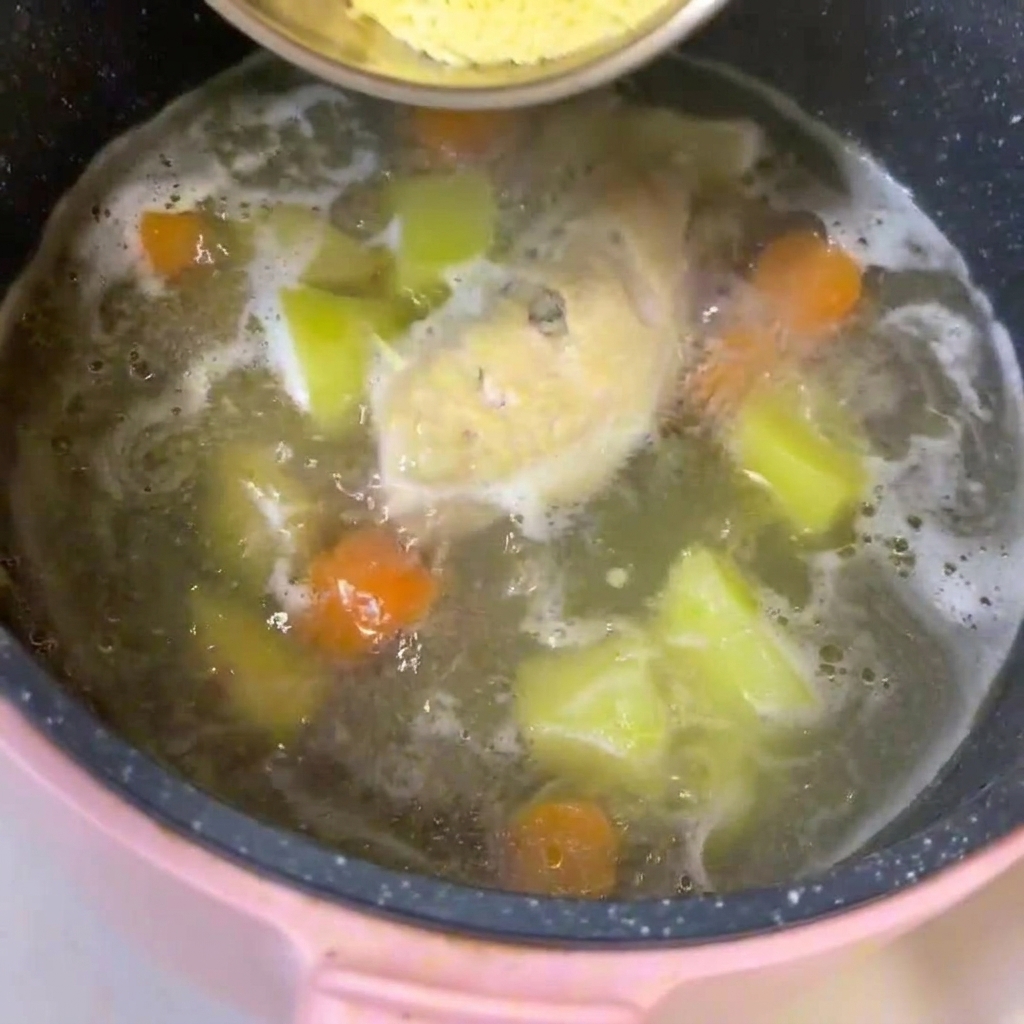 닭고기, 깍둑썰기한 감자와 당근이 끓고 있는 냄비에 아기용 국수를 넣고 젓는 모습.