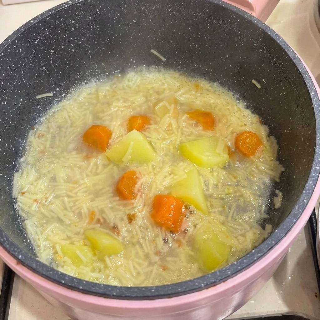 뼈를 발라낸 닭고기를 푹 익은 국수와 감자, 당근이 담긴 냄비에 다시 넣는 모습.