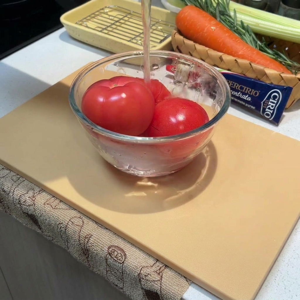 유리볼에 담긴 통토마토에 뜨거운 물을 붓고 있는 클로즈업 사진.