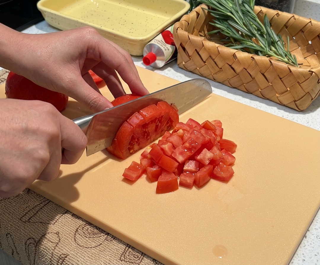 껍질을 벗긴 신선한 토마토를 작고 일정한 크기로 다지고 있는 모습.