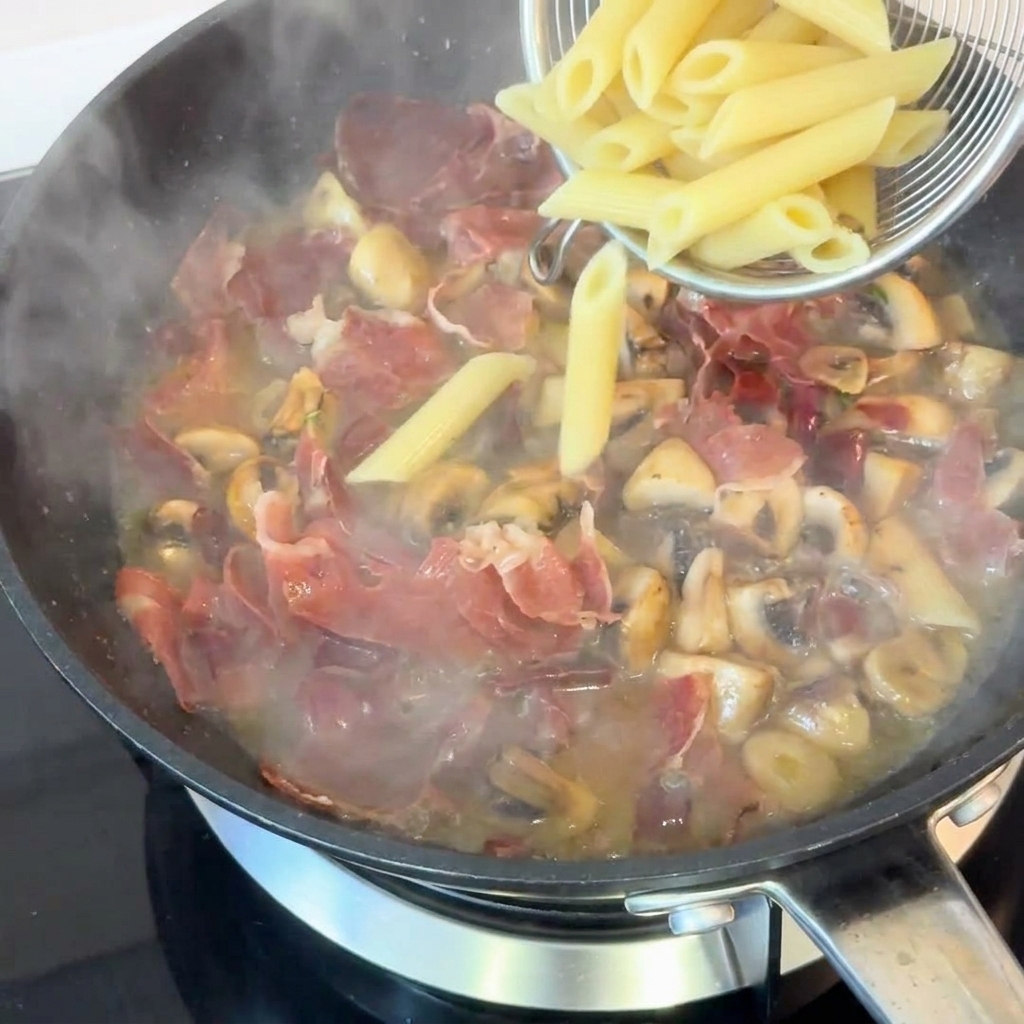 삶은 펜네 파스타를 소스 팬에 넣고 볶는 모습.
